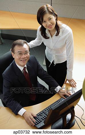 Businessman and woman in office cubicle, looking up at camera View Large Photo Image Stock Image - Businessman and woman in office cubicle, looking up at camera. Fotosearch