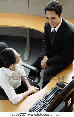 Businessman and woman in office cubicle, having a discussion View Large Photo Image Stock Photo - Businessman and woman in office cubicle, having a discussion. Fotosearch
