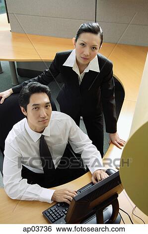 Businessman and woman in office cubicle, looking up at camera View Large Photo Image Stock Photograph - Businessman and woman in office cubicle, looking up at camera. Fotosearch