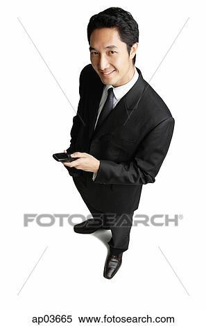 Businessman holding mobile phone, smiling at camera View Large Photo Image Stock Photography - Businessman holding mobile phone, smiling at camera . Fotosearch