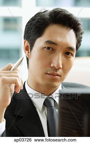 Businessman holding pen, looking camera View Large Photo Image Stock Photograph - Businessman holding pen, looking camera. Fotosearch