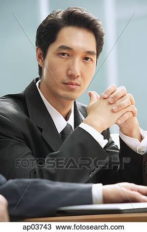 Businessman looking at camera, hands clasped View Large Photo Image Stock Image - Businessman looking at camera, hands clasped. Fotosearch