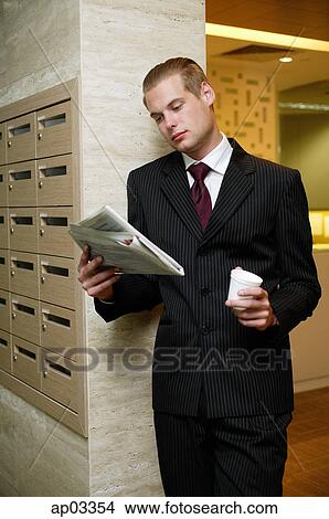 Picture - Businessman reading newspaper and holding paper cup . Fotosearch