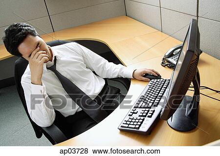 Businessman sitting at desk, hand covering face View Large Photo Image Stock Photo - Businessman sitting at desk, hand covering face. Fotosearch