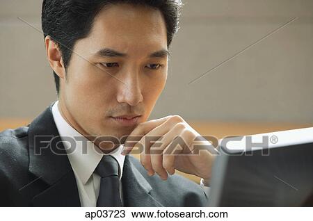 Businessman sitting at desk, looking at computer monitor, hand on chin View Large Photo Image Stock Image - Businessman sitting at desk, looking at computer monitor, hand on chin . Fotosearch