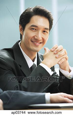 Picture - Businessman smiling at camera, hands clasped . Fotosearch