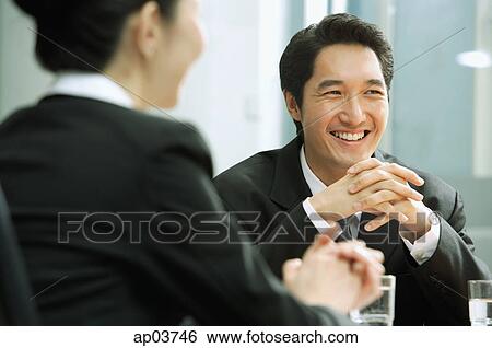 Stock Photograph - Businessman smiling, hands clasped, woman in the foreground. Fotosearch