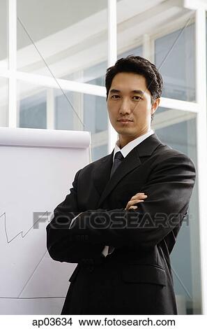 Businessman standing next to flipchart, arms crossed View Large Photo Image Picture - Businessman standing next to flipchart, arms crossed. Fotosearch