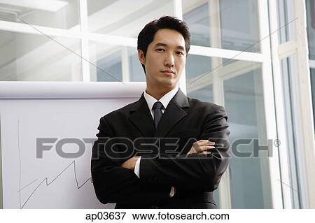 Businessman standing next to flipchart, looking at camera View Large Photo Image Stock Photo - Businessman standing next to flipchart, looking at camera. Fotosearch