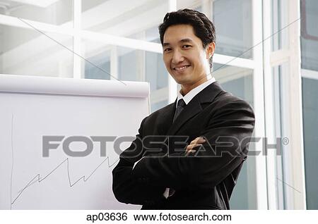 Businessman standing next to flipchart, smiling, arms crossed View Large Photo Image Stock Photograph - Businessman standing next to flipchart, smiling, arms crossed . Fotosearch