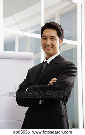 Businessman standing next to flipchart, smiling View Large Photo Image Stock Photography - Businessman standing next to flipchart, smiling. Fotosearch