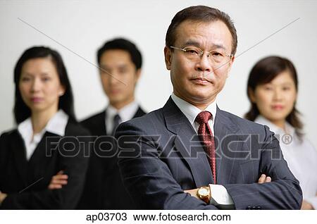 Businessman with arms crossed, people in the background View Large Photo Image Stock Image - Businessman with arms crossed, people in the background . Fotosearch