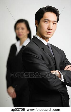 Businessman with arms crossed, woman in the background View Large Photo Image Stock Photograph - Businessman with arms crossed, woman in the background . Fotosearch