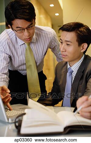 Businessmen working together, looking at laptop View Large Photo Image Stock Image - Businessmen working together, looking at laptop. Fotosearch