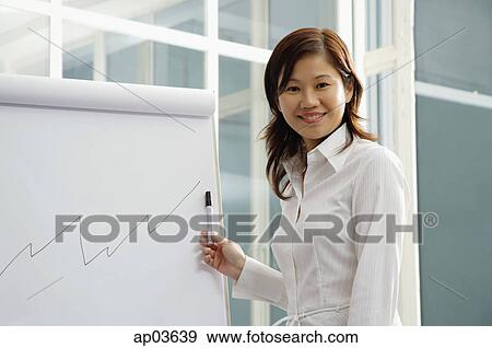 Businesswoman looking at camera, standing next to flipchart View Large Photo Image Stock Photo - Businesswoman looking at camera, standing next to flipchart. Fotosearch