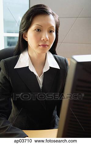 Businesswoman sitting at desk, using computer View Large Photo Image Stock Image - Businesswoman sitting at desk, using computer. Fotosearch
