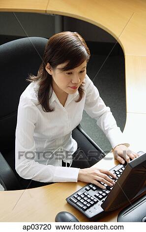 Businesswoman sitting in office cubicle, using computer View Large Photo Image Stock Image - Businesswoman sitting in office cubicle, using computer . Fotosearch