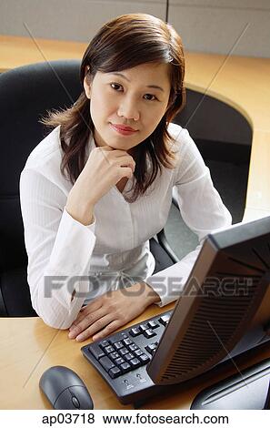 Businesswoman sitting in office cubicle, looking at camera View Large Photo Image Stock Photo - Businesswoman sitting in office cubicle, looking at camera . Fotosearch
