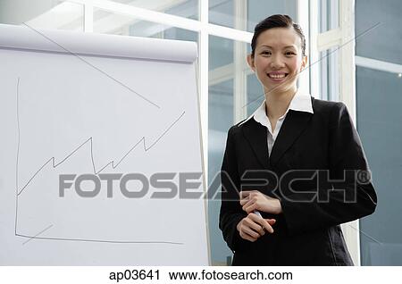 Businesswoman standing next to flipchart, smiling at camera View Large Photo Image Stock Image - Businesswoman standing next to flipchart, smiling at camera . Fotosearch