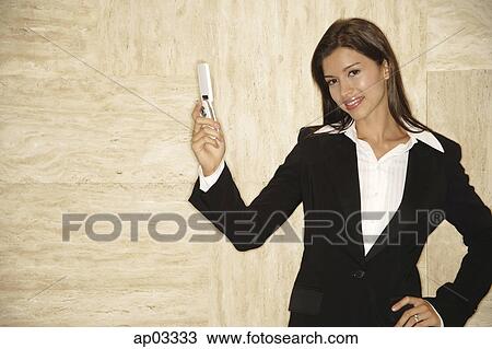 Businesswoman with mobile phone, looking at camera, hand on hip View Large Photo Image Stock Image - Businesswoman with mobile phone, looking at camera, hand on hip . Fotosearch