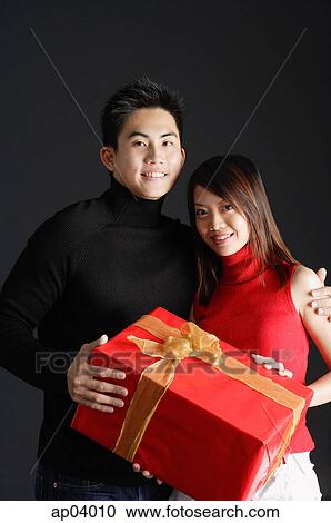 Couple holding gift, looking at camera View Large Photo Image Stock Image - Couple holding gift, looking at camera . Fotosearch