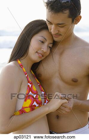 Stock Image - Couple holding hands, woman leaning on mans shoulder. Fotosearch