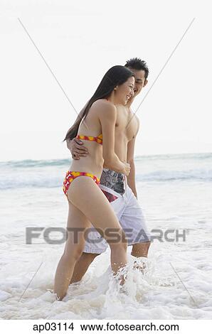 Picture - Couple on beach, ankle deep in water. Fotosearch