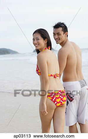 Couple on beach, looking over shoulder at camera View Large Photo Image Stock Image - Couple on beach, looking over shoulder at camera. Fotosearch