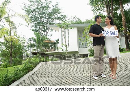 Couple on driveway holding for sale sign View Large Photo Image Stock Photo - Couple on driveway holding for sale sign . Fotosearch