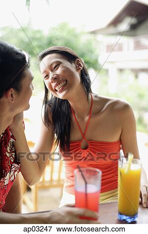 Stock Photo - Couple sitting face to face, woman touching mans face . Fotosearch