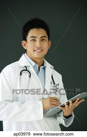 Doctor holding clipboard, looking at camera View Large Photo Image Stock Photo - Doctor holding clipboard, looking at camera. Fotosearch