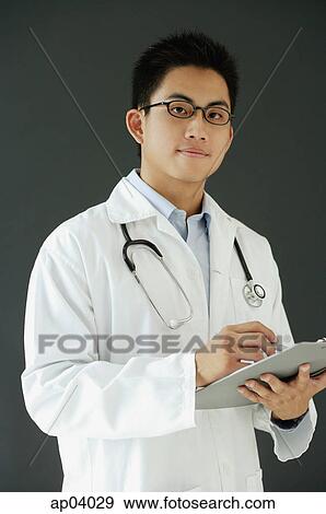 Doctor holding clipboard, looking at camera View Large Photo Image Stock Photo - Doctor holding clipboard, looking at camera . Fotosearch