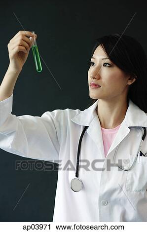 Doctor looking at test tube filled with green liquid View Large Photo Image Stock Image - Doctor looking at test tube filled with green liquid . Fotosearch