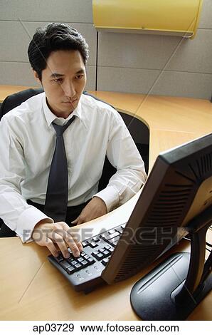 Executive sitting in cubicle looking at computer View Large Photo Image Stock Photo - Executive sitting in cubicle looking at computer . Fotosearch