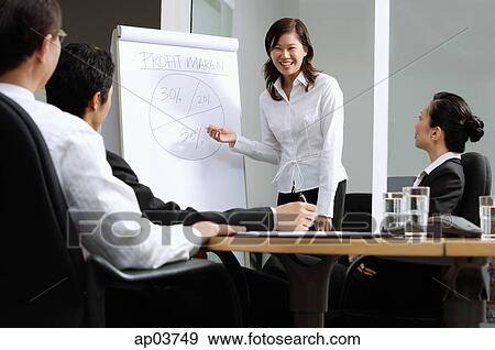 Executives having a business meeting, woman standing next to flipchart View Large Photo Image Stock Photo - Executives having a business meeting, woman standing next to flipchart . Fotosearch