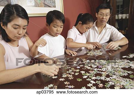 Stock Photography - Family of four fixing jigsaw puzzle . Fotosearch