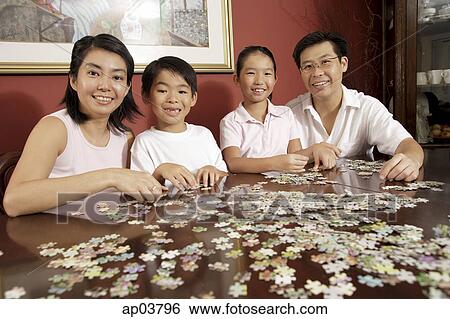 Family of four in living room working on jigsaw puzzle View Large Photo Image Stock Photograph - Family of four in living room working on jigsaw puzzle . Fotosearch