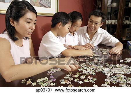 Stock Photo - Family of four working on jigsaw puzzle . Fotosearch