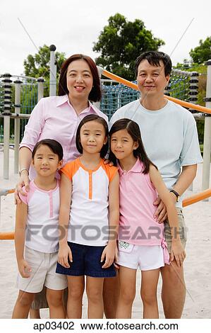 Stock Image - Family standing at playground, smiling at camera . Fotosearch