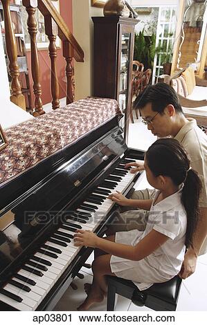Stock Image - Father and daughter playing piano. Fotosearch