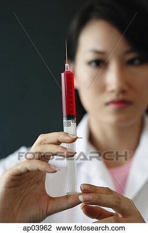 Stock Image - Female doctor holding syringe. Fotosearch