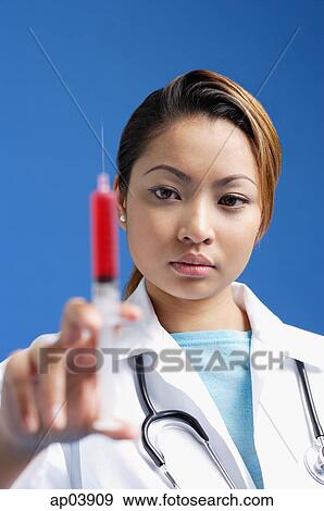 Stock Photo - Female doctor holding syringe. Fotosearch