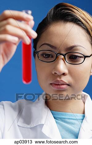 Female technician looking at test tube filled with red liquid View Large Photo Image Stock Image - Female technician looking at test tube filled with red liquid . Fotosearch