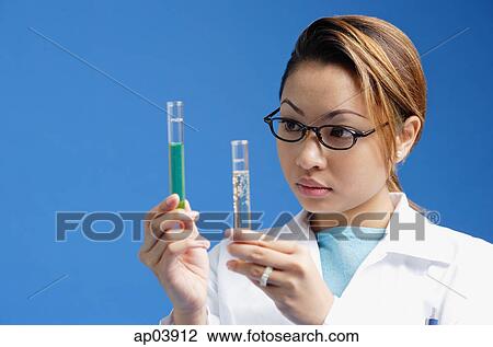 Stock Image - Female technician looking at test tubes. Fotosearch