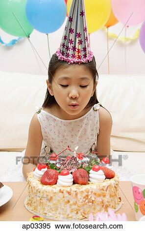 Stock Photography - Girl blowing out candle on a cake . Fotosearch