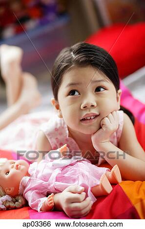 Girl holding a doll, looking up, hand on chin View Large Photo Image Stock Photograph - Girl holding a doll, looking up, hand on chin. Fotosearch