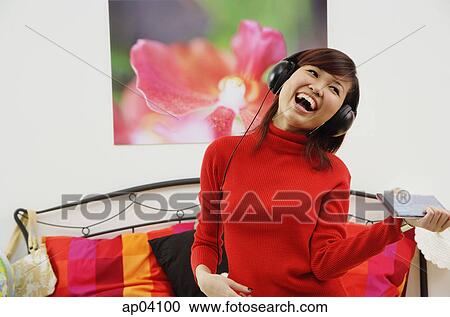 Girl in bedroom, listening to headphone, smiling View Large Photo Image Stock Image - Girl in bedroom, listening to headphone, smiling . Fotosearch