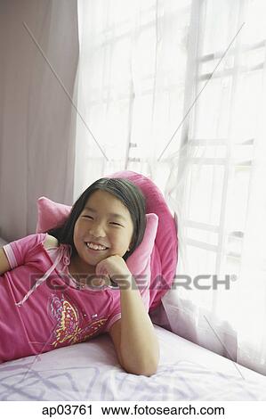 Girl in bedroom, lying on bed, hand on chin View Large Photo Image Stock Image - Girl in bedroom, lying on bed, hand on chin . Fotosearch