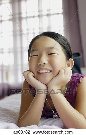 Girl in bedroom, lying on bed, hands on chin View Large Photo Image Stock Image - Girl in bedroom, lying on bed, hands on chin. Fotosearch