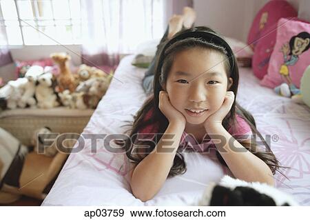 Girl in bedroom, lying on bed, hands on chin, looking at camera View Large Photo Image Stock Photo - Girl in bedroom, lying on bed, hands on chin, looking at camera . Fotosearch